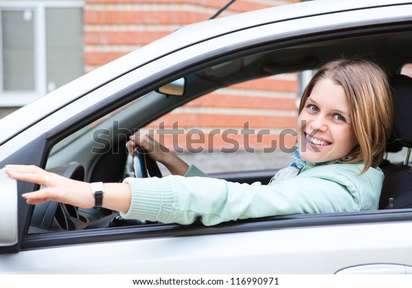 Young driver\
a blond woman holding back car\
mirror