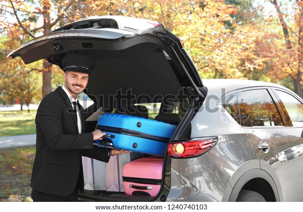 Young\
driver loading suitcases into car trunk\
outdoors