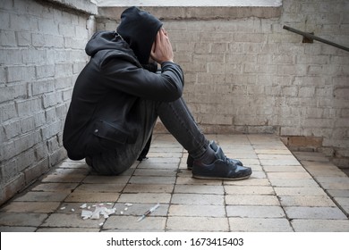 A Young Drug Addict Experiencing A Drug Addiction Crisis, Sitting In An Abandoned House. Addiction Concept. Lifestyle.