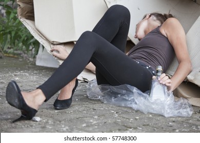 young drunk woman with bottle in her hand sleeping outdoor