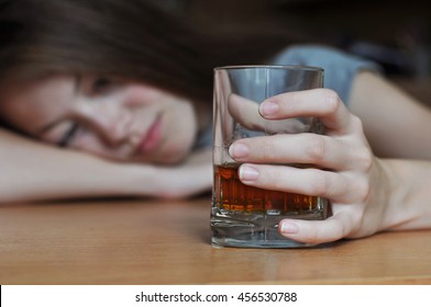 Young drunk woman holding a glass of whiskey