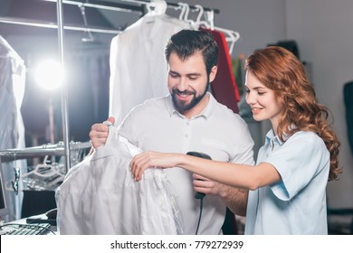 Young Dry Cleaning Workers Scanning Barcode On Bag With Shirt