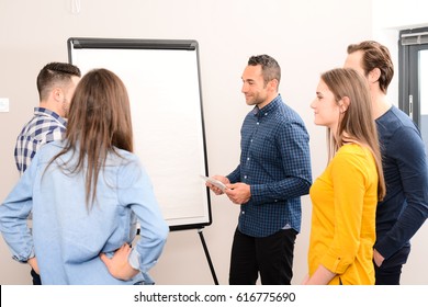 Young Dynamic Business Team Man And Woman Discussing Around A Flip Chart White Board In Meeting Room