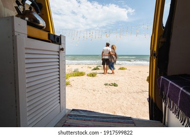 Young Eastern European couple travelling by yellow camper van along the seaside and chilling out at the beach. Self built off-grid motorhome camping in the wild nature.