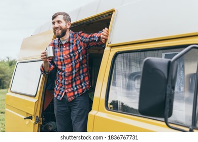 Young Eastern European man travelling by yellow camper van though the countryside. Self built off-grid motorhome camping in the wild nature.
