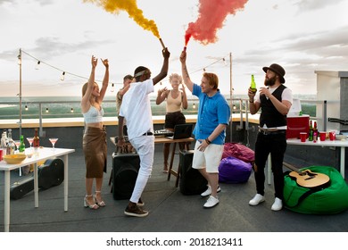 Young ecstatic friends using firecrackers with red and yellow smoke while dancing - Powered by Shutterstock