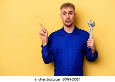 Young Electrician Caucasian Man Isolated On Yellow Background Pointing To The Side