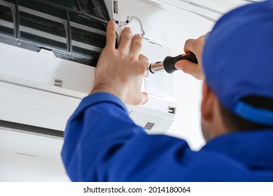Young electrician repairing air conditioner indoors