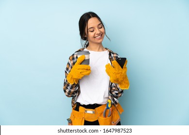 Young electrician woman isolated on blue background holding coffee to take away and a mobile - Powered by Shutterstock