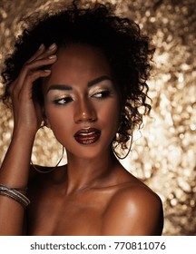 young elegant african american woman with afro hair. Glamour makeup. Golden Background. 