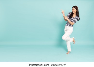 Young elegant beautiful Asian woman smiling and pointing to empty copy space isolated on green background, Full body composition