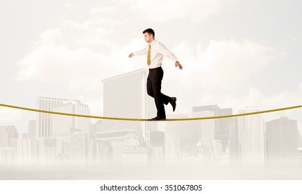 A Young Elegant Businessman Walking On Tight Golden Rope In Front Of City Buildings Landscape Background Concept