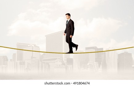 A Young Elegant Businessman Walking On Tight Golden Rope In Front Of City Buildings Landscape Background Concept