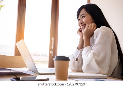 Young elegant businesswoman in white shirt and cup of coffee sitting with laptop in cafe. Dreaming Positive thinking person concept.