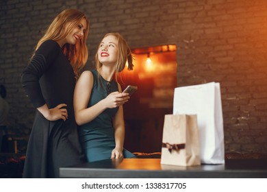 Young and elegant girls are sitting at the restaurant and use the phone - Shutterstock ID 1338317705