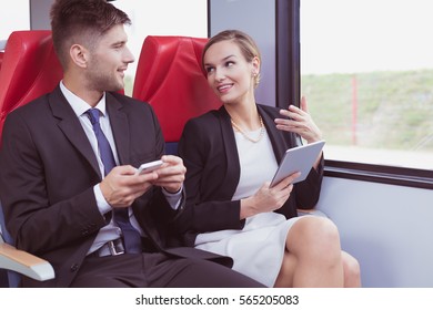 Young elegant man and pretty woman with tablet talking in train