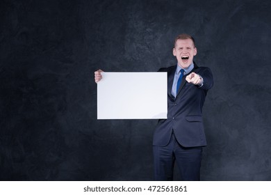 Young Elegant Man In Suit, Holding A Piece Of Paper, Pointing Something In Front Of Him And Shouting