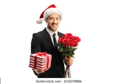 Young elegant man wearing a suit and a Santa hat holding roses and a present isolated on white backgound