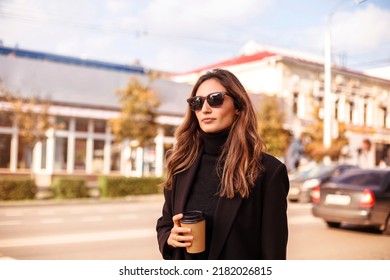 Young Elegant Stylish Woman In Black Clothes And Sunglasses Holding Take Away Coffee Cup While Walking City Street, Beautiful Business Lady Outdoors