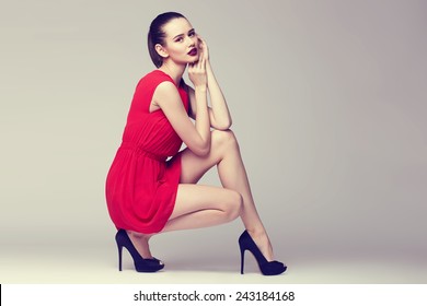 young elegant woman in red dress and black shoes, fashion studio shot 