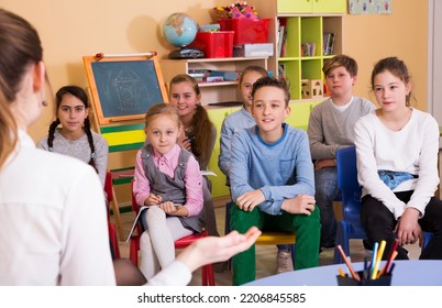Young Elementary Age Children Sitting And Listening Teacher At Class