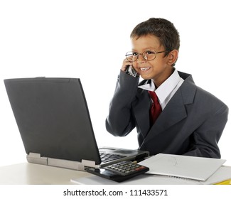 A young elementary boy delightedly talking on the phone behind his computer while wearing his dad's business suit.  On a white background. - Powered by Shutterstock