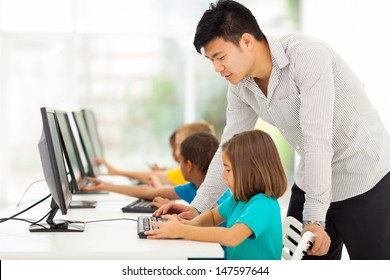 Young Elementary School Teacher Teaching Students In Computer Room