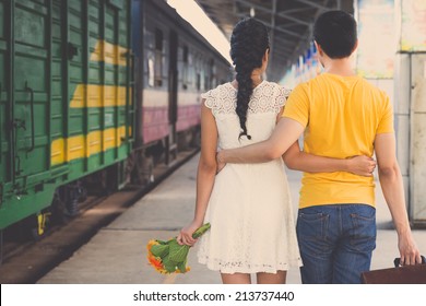 Young Embracing Couple Walking Along The Platform, Rear View