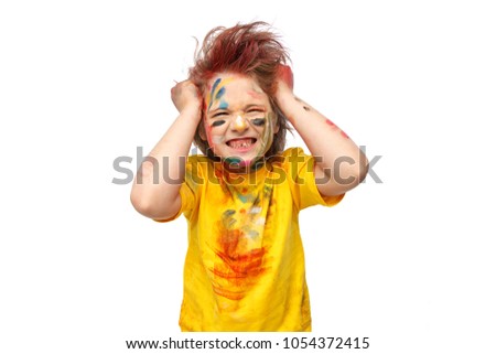 Young emotional boy, his face and hands painted with paints, vivid emotions, messy hair, yellow t-shirt
