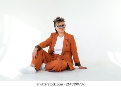 Young Emotional Non Binary Person Wearing Orange Color Suit Posing At Studio