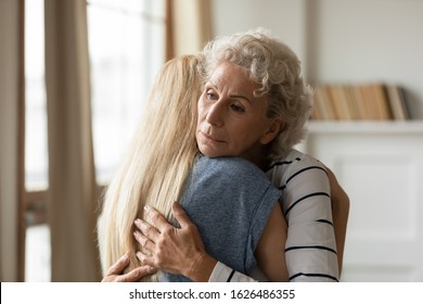 Young empathic woman embracing soothing comforting frustrated older mature mother. Grownup daughter apologizing to offended middle aged mommy. Two female generations family overcoming grief together.