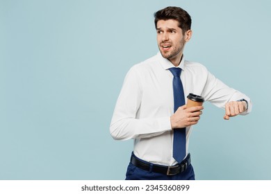 Young employee IT business man corporate lawyer wear classic formal shirt tie smart watch check time work in office hold takeaway coffee to go hurry up isolated on plain pastel light blue background - Powered by Shutterstock