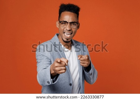 Young employee business man corporate lawyer wear classic formal grey suit shirt glasses work in office point index finger camera on you motivating encourage isolated on plain red orange background
