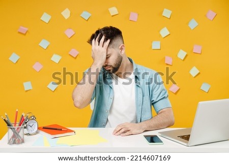 Young employee business man in shirt sit work at white office desk with pc laptop put hand on face facepalm epic fail gesture isolated on yellow background studio portrait. Achievement career concept