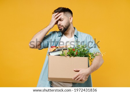 Young employee business man wear shirt stand work white office desk pc laptop hold cardboard box with stuff put hand on face facepalm epic fail gesture isolated on yellow background studio portrait.