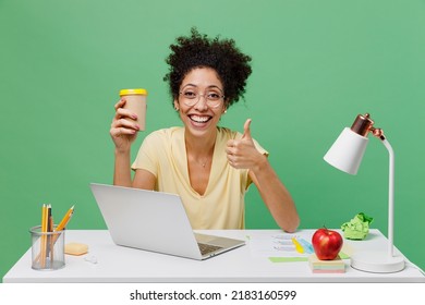 Young Employee Business Woman Of African American Ethnicity In Shirt Sit Work At White Office Desk Pc Laptop Hold Takeaway Delivery Cup Coffee To Go Show Thumb Up Isolated On Plain Green Background