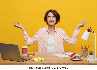 Young employee business woman wear shirt sit work at office desk with pc laptop hold spread hands in yoga om aum gesture meditate isolated on plain yellow color background. Achievement career concept - Powered by Shutterstock