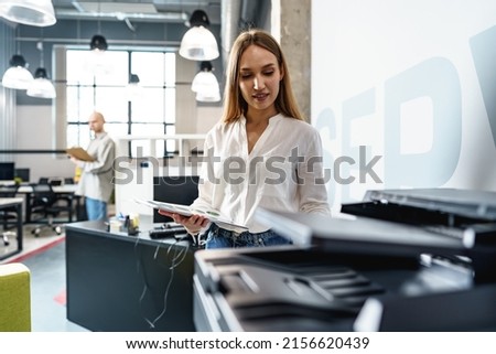 Young employee using modern printer in office