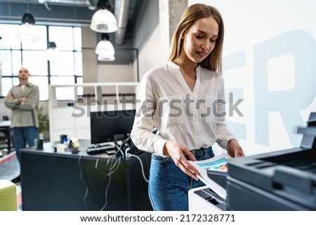 Young employee using modern printer in office