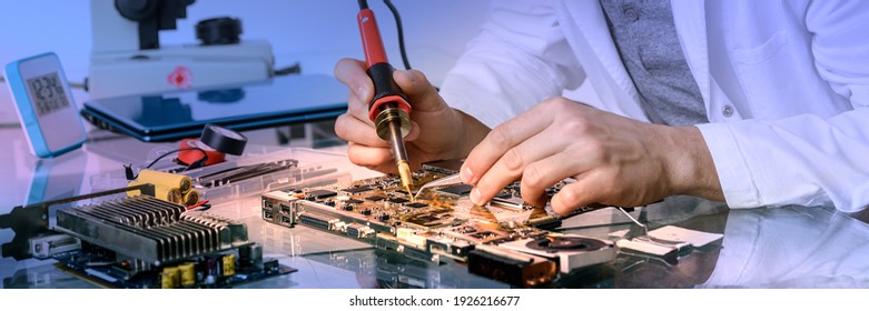 Young energetic male tech or engineer repairs electronic equipment in research facility. Shallow DOF, focus on the face and hands of the worker. - Powered by Shutterstock