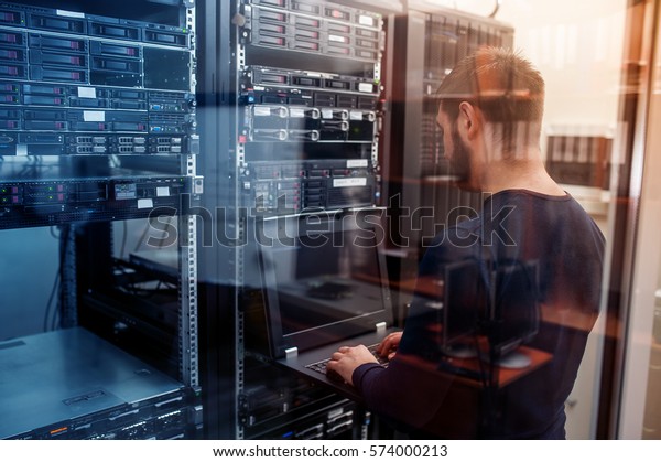 young it engeneer business man with\
thin modern aluminium laptop in network server\
room