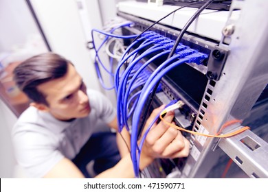 Young Engeneer Man In Network Server Room Connecting Wires