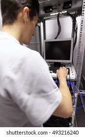 Young engeneer man in network server room connecting wires