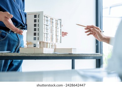 A young engineer or architect is talking and discussing with a senior or her boss, they are drawing graphic design of construction project plan, and discussing for improvement  at desk with blueprint  - Powered by Shutterstock