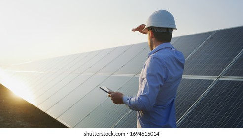 An young engineer is checking with tablet an operation of sun and cleanliness on field of photovoltaic solar panels on a sunset. Concept:renewable energy, technology,electricity,service, green,future  - Powered by Shutterstock