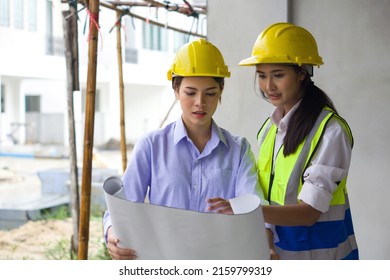 Young engineer in a construction helmet and safety vest explaining to project owner about a floor plan. Work environment of engineers at the construction site of housing projects.