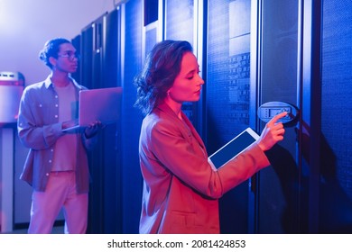 young engineer with digital tablet checking server near african american colleague with laptop