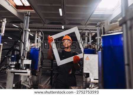 Young engineer holding a window frame in a pvc window factory, ensuring product quality and checking for defects