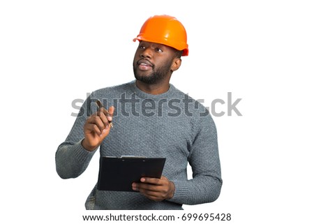 Young engineer inspecting construction. Handsome afro american architect with clipboard close up. Attractive project manager with helmet and clipboard on white background.