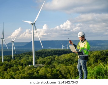 Young engineer looks at and inspects wind turbines on a plateau using a digital tablet. - Powered by Shutterstock